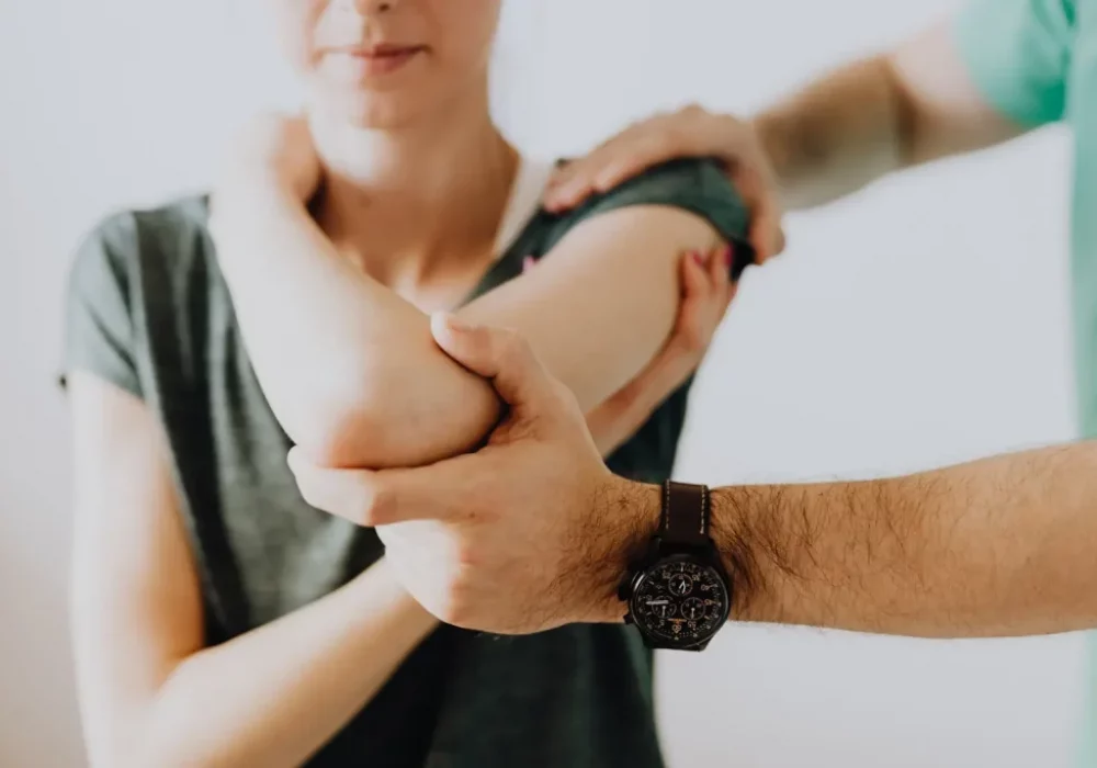 Therapist stabilizing a patient’s forearm during arm rehabilitation therapy in a clinical setting.